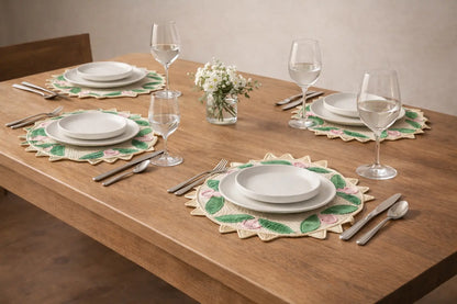 Dining table set with plates, glasses, and cutlery on decorative placemats.
