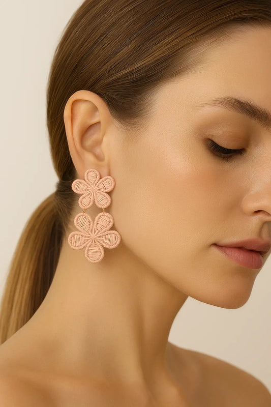 Close-up of a woman wearing pink floral earrings against a neutral background